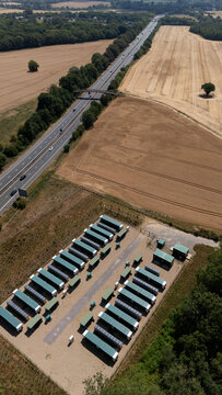 Aerial view of a data centre with rows of modular units situated next to a highway and agricultural fields in Hatfield, England, United Kingdom.