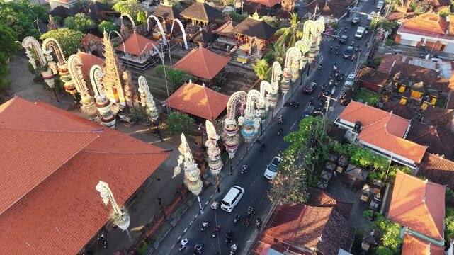 Aerial view of Pura Agung Petilan temple complex with traditional penjor decorations lining the street in Kecamatan Denpasar Timur, Bali, Indonesia.