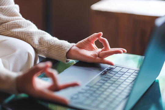Closeup image of a woman hands in lotus pose over laptop computer for stress relief concept