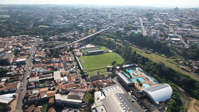 Aerial view of a soccer field and swimming pools surrounded by urban residential buildings and a bridge in Botucatu, State of Sao Paulo, Brazil.