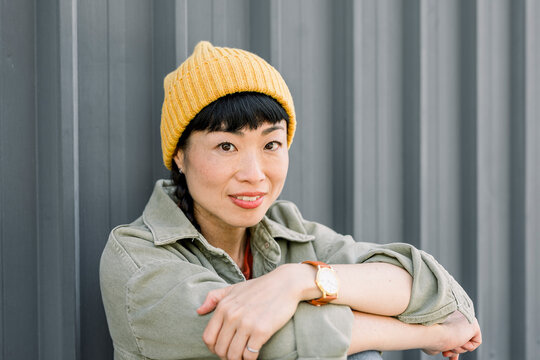 Portrait of smiling woman in urban setting wearing casual jacket and beanie