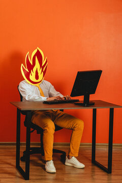 Man with fire mask works at office desk during burnout