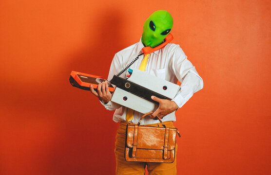 Overwhelmed man in alien mask holding retro telephone and binders