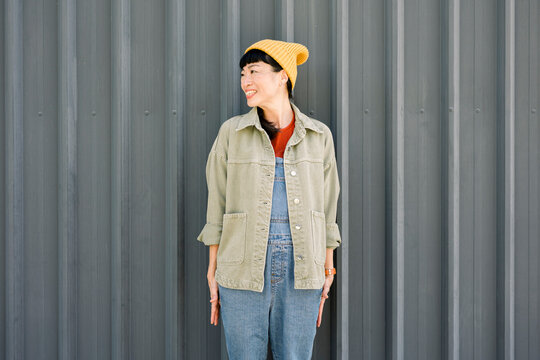 Laughing woman in casual urban outfit with yellow beanie and jacket