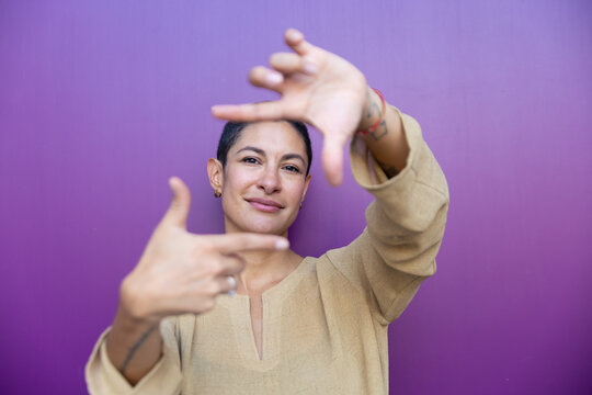 Businesswoman makes a hand frame gesture against a purple background