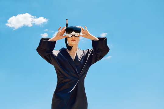 Woman holds virtual reality snorkel mask against blue sky