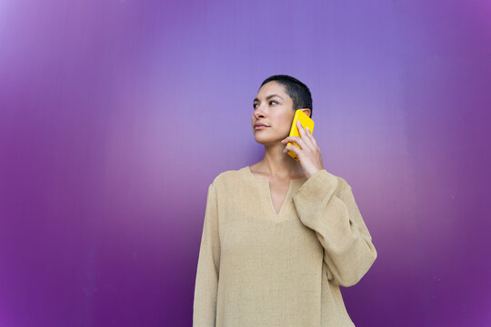 Confident business professional talking on smartphone by purple wall