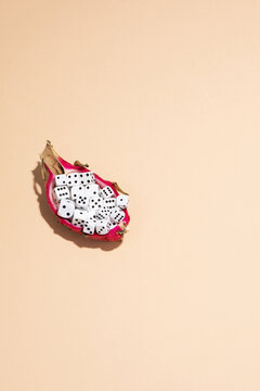 Dragon fruit half filled with white dice lies on a beige background