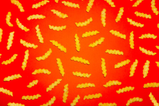 A salty potato snack creates a pattern on a bright red background