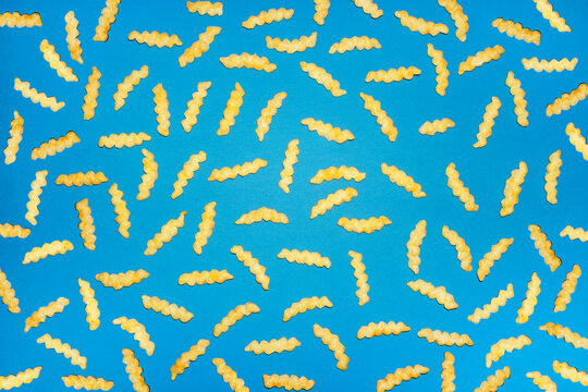 Crinkle cut french fries form a random pattern on a blue background