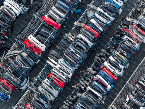 Aerial view of organized rows of salvaged car bumpers and automotive body parts stacked in a recycling facility in Poland.