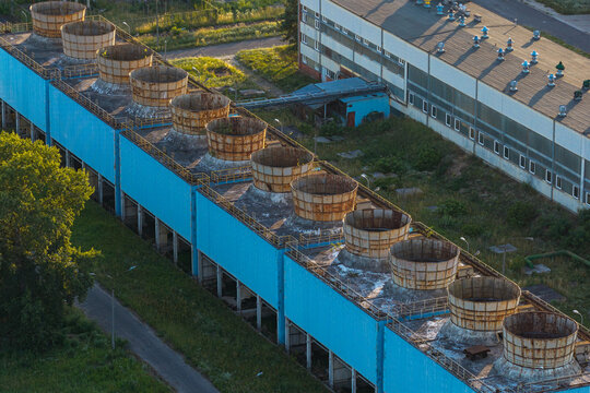 Aerial view of an old pharmaceutical facility with rusted cooling towers on a blue industrial building in Poland.