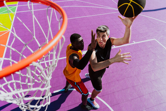 Man dunks basketball during a game on an outdoor court