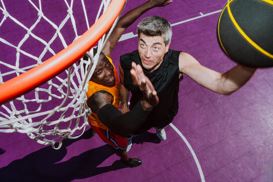 Men play a competitive basketball game on the outdoor court