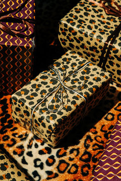 Stylish holiday gifts sit on a leopard texture surface