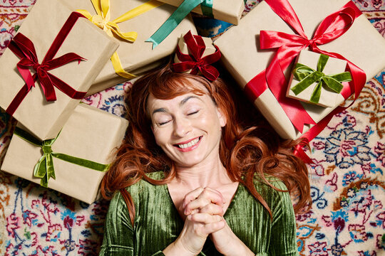 Happy woman in green dress expects Christmas gift on Persian rug