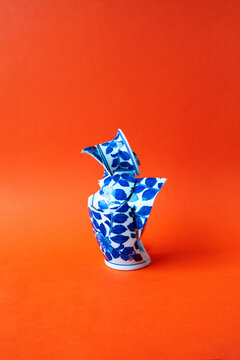Conceptual broken blue porcelain vase on red background