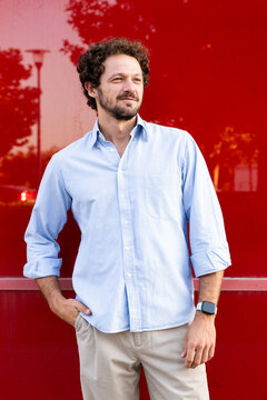 Confident businessman wears a blue shirt near a red wall