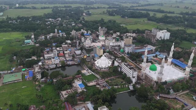 Aerial view of the Maizbhandar Darbar Sharif mosque complex surrounded by lush green fields and rural buildings in Fatikchhari Upazila, Chittagong Division, Bangladesh.