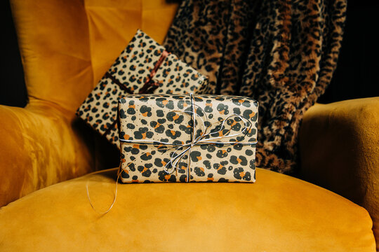 Stylish leopard print holiday gifts rest on a yellow armchair