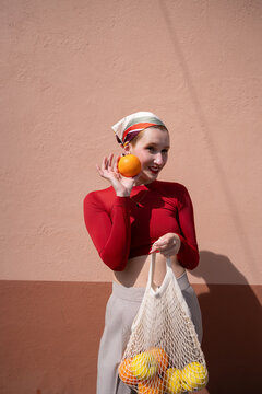 Young woman holds fresh orange with reusable bag