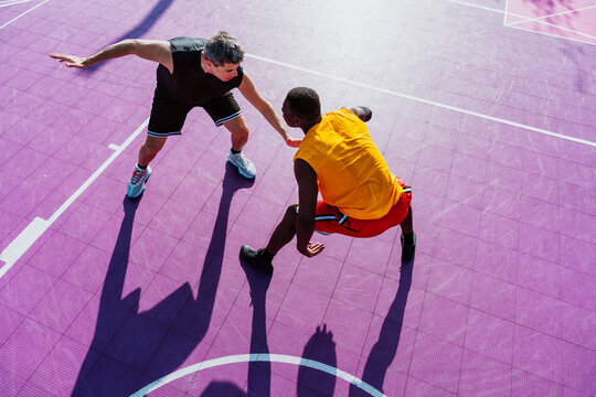 Male athlete defends opponent during streetball game on purple court
