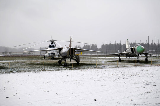 View of military aircraft including a helicopter and fighter jets displayed on a snowy field in Pasvalys, Panevezys County, Lithuania.