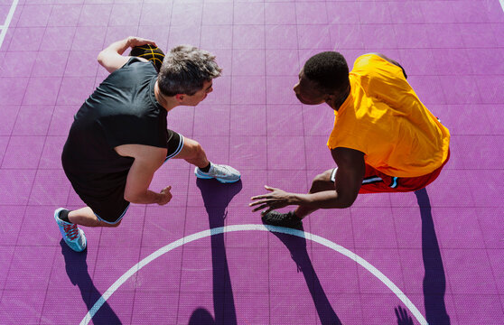 Athletes play a competitive game of streetball on a purple court