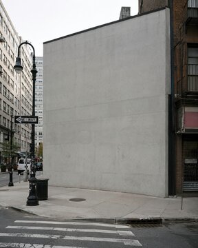 Empty concrete wall on urban building corner, blank mockup space with street lamp, overcast city street