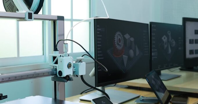 Desktop 3d printer in a modern workspace with dual monitors 3d design software and a laptop on the desk.