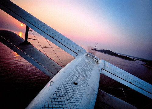 Aerial view of the biplane wing flying over the Adriatic Sea near the Koversada resort at sunset in Vrsar, Istria County, Croatia.