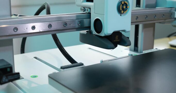 Close-up of a 3d printer head working over the build plate in a modern workshop, precision manufacturing and digital fabrication.