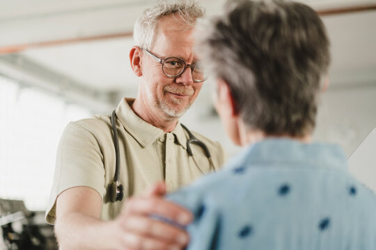 Compassionate male doctor comforts a female patient indoors