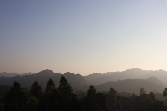 View of the hilly landscape with lush trees in the foreground and misty mountains in the background under a soft sky in Cox's Bazar, Chittagong Division, Bangladesh.