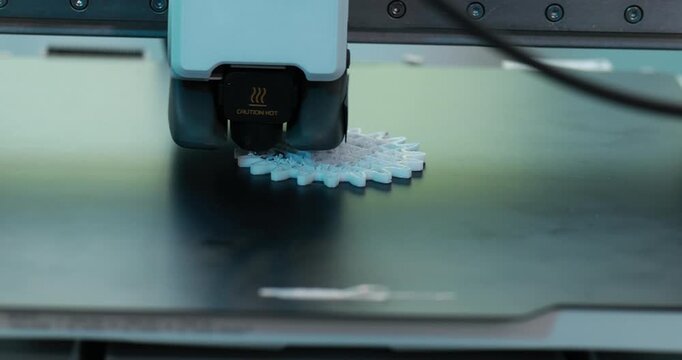Close-up of a 3d printer producing a small plastic object on the build plate in a modern workshop