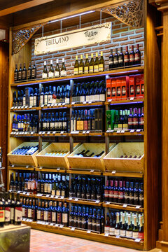 A well-organized wine display with multi-tiered wooden shelving units and various shapes and sizes of red