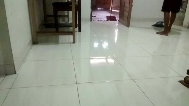 A man is sweeping the floor in a dirty, dusty family room, capturing a moment of cleanliness and tidiness amidst a cozy atmosphere.