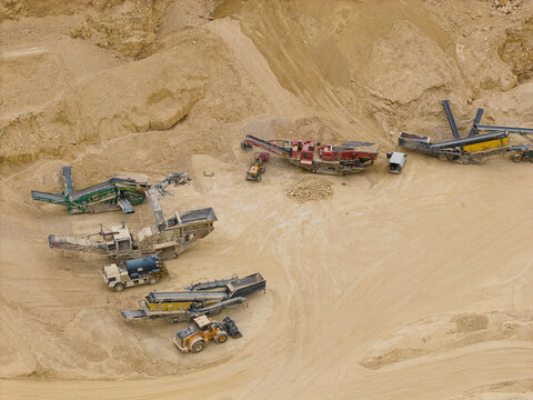 Aerial view of aggregates quarry and mining site with heavy machinery, conveyor belts, and earth-moving equipment in Little Ponton, England, United Kingdom.