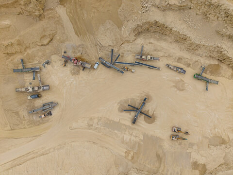 Aerial view of aggregates quarry and mining site with heavy machinery, conveyor belts, and earthmoving equipment in Little Ponton, England, United Kingdom.