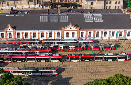 Aerial view of Nowy Port tram depot with rows of red and white trams parked beside a historic industrial building in Gdansk, Pomeranian Voivodeship, Poland.