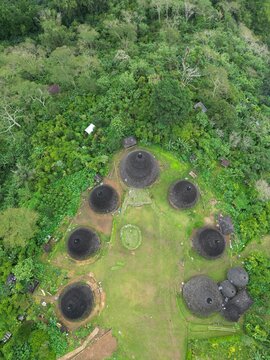 Aerial view of Waerebo Village with its traditional conical houses surrounded by lush green forest in Satar Mese Barat, East Nusa Tenggara, Indonesia.