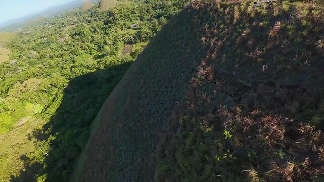 FPV aerial view of the iconic grass-covered limestone mounds of the Chocolate Hills in Batuan, Central Visayas, Philippines.