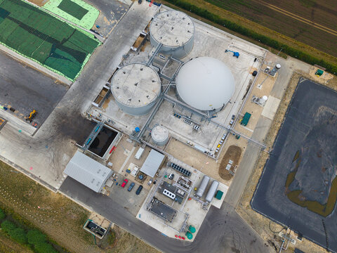 Aerial view of the Moor Bio Energy facility featuring large circular storage tanks, a white dome-shaped digester, industrial piping, and paved grounds in Grantham, England, United Kingdom.