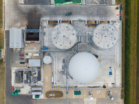 Aerial view of Moor Bio Energy biomass plant featuring large circular digester tanks, industrial piping, and facility infrastructure in Grantham, England, United Kingdom.