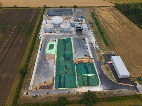Aerial view of Moor Bio Energy biomass plant featuring large storage silos, a white dome, and green covered silage clamps surrounded by agricultural fields in Grantham, England, United Kingdom.