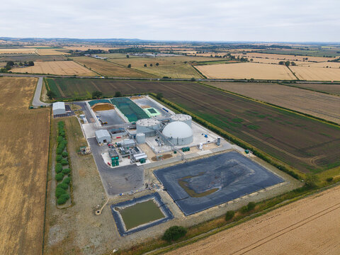 Aerial view of the Moor Bio Energy biomass plant featuring large anaerobic digester tanks, storage facilities, and surrounding agricultural fields in Grantham, England, United Kingdom.