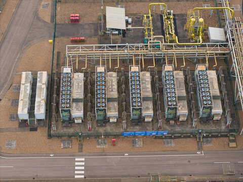 Aerial view of Staythorpe Power Station featuring rows of cooling units, industrial piping, and technical infrastructure within a fenced facility in Staythorpe, England, United Kingdom.
