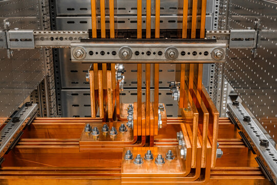 View of copper busbars and electrical components inside an industrial power distribution panel in Latvia.
