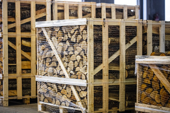View of stacked firewood in wooden crates wrapped with plastic film in a storage facility in Latvia.