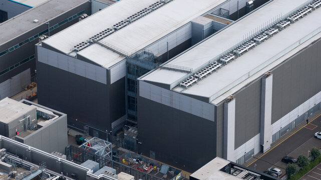 Aerial view of a large modern industrial data center building featuring extensive rooftop cooling systems and metal cladding in Slough, England, United Kingdom.